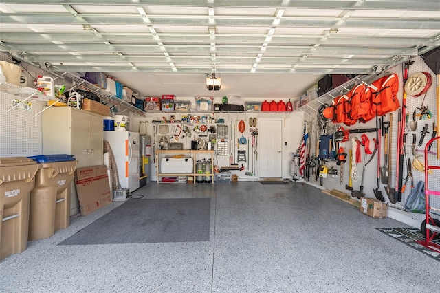 garage with white fridge, water heater, a workshop area, and a garage door opener