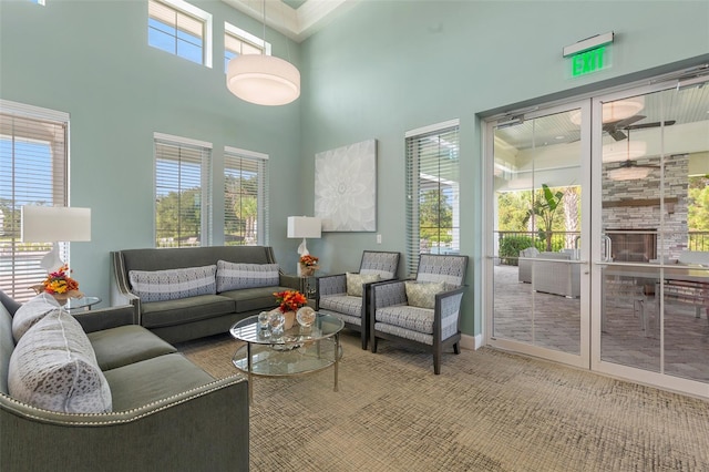 living room with light colored carpet, a high ceiling, french doors, and a fireplace