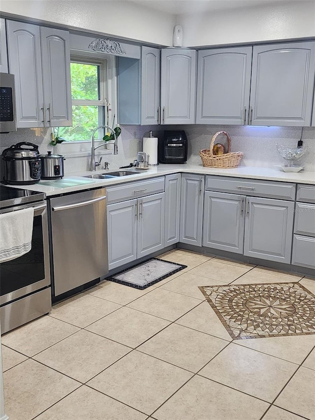 kitchen with sink, appliances with stainless steel finishes, backsplash, and light tile floors