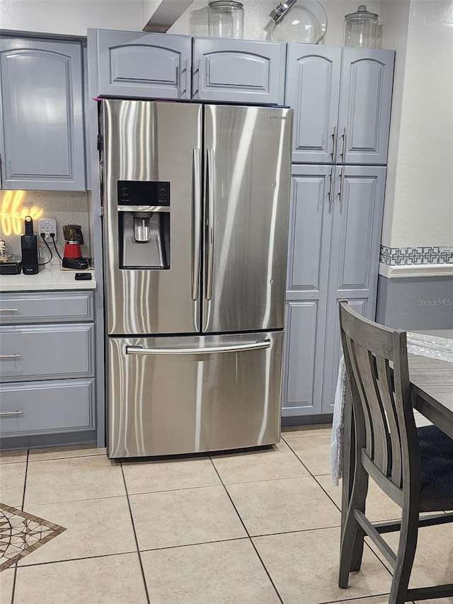 kitchen featuring stainless steel refrigerator with ice dispenser, light tile floors, and gray cabinetry