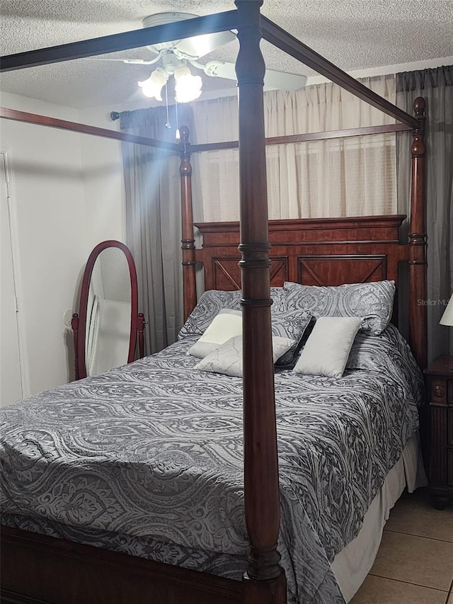 bedroom with tile floors, ceiling fan, and a textured ceiling