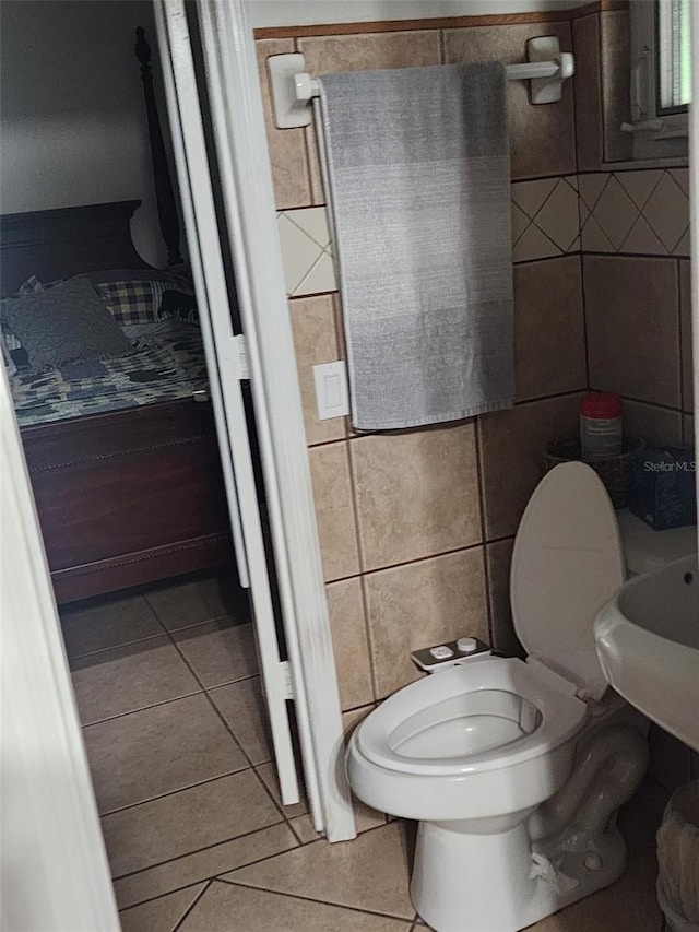 bathroom featuring tile walls, toilet, and tile flooring