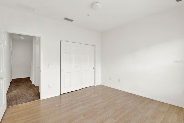 unfurnished bedroom featuring light colored carpet and a closet