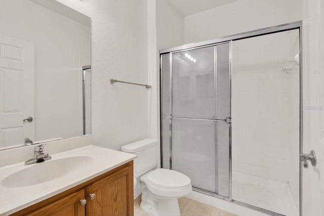 bathroom with tile flooring, walk in shower, vanity with extensive cabinet space, and toilet