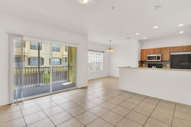 kitchen with tasteful backsplash, light tile flooring, hanging light fixtures, refrigerator, and an inviting chandelier