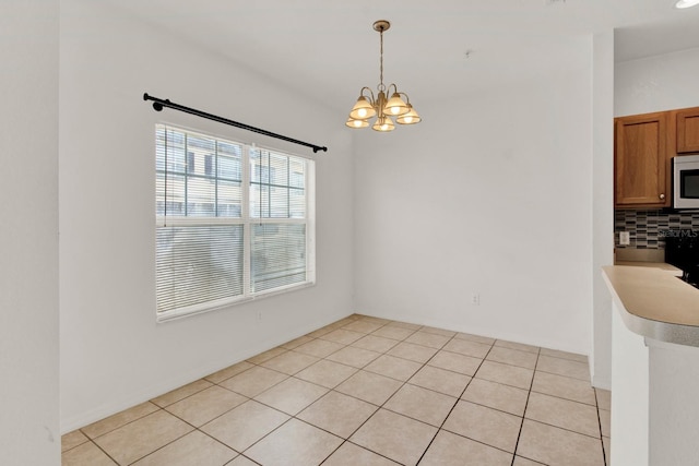 unfurnished room with a chandelier and light tile floors