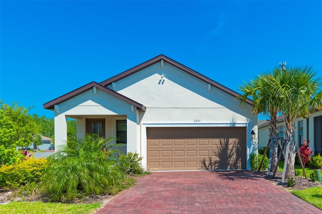 view of front facade featuring decorative driveway, an attached garage, and stucco siding