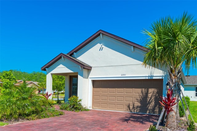 view of front of property featuring an attached garage, decorative driveway, and stucco siding