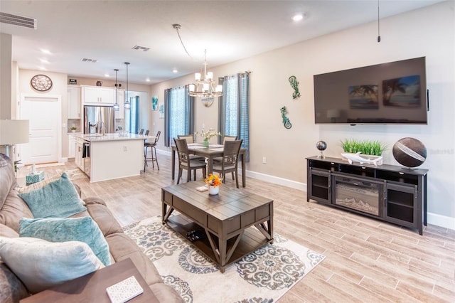 living room featuring a chandelier and light wood-type flooring