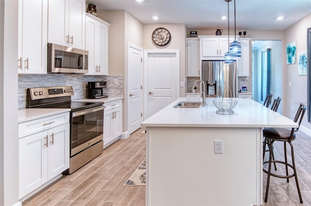 kitchen with sink, tasteful backsplash, stainless steel appliances, a center island with sink, and pendant lighting