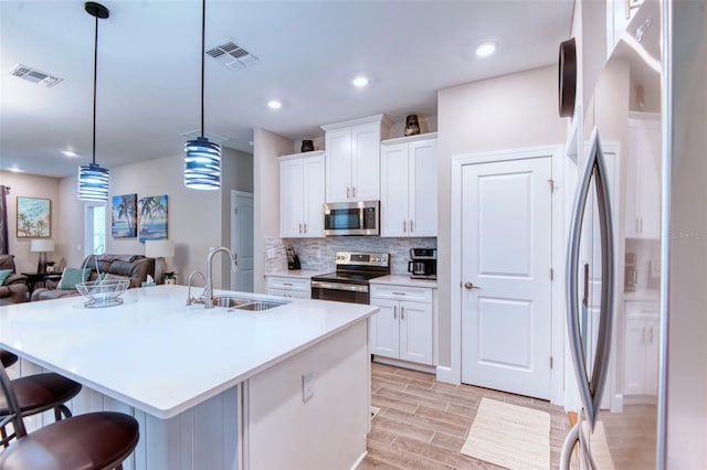 kitchen featuring backsplash, sink, stainless steel appliances, and white cabinetry