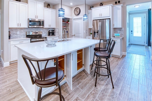 kitchen featuring backsplash, pendant lighting, stainless steel appliances, and a kitchen bar