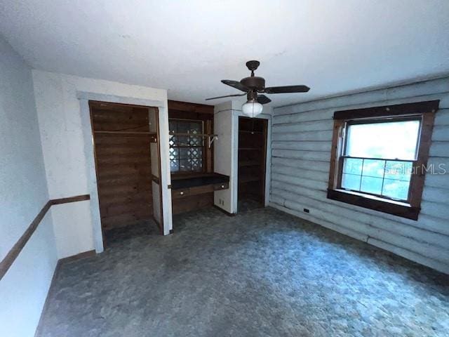 unfurnished bedroom with dark colored carpet and ceiling fan