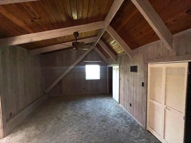 additional living space with vaulted ceiling with beams, wood walls, and wood ceiling