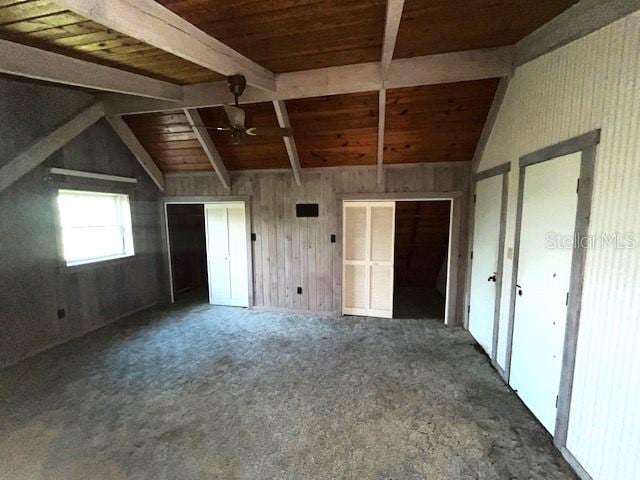 interior space featuring wooden ceiling, wood walls, dark colored carpet, and vaulted ceiling with beams