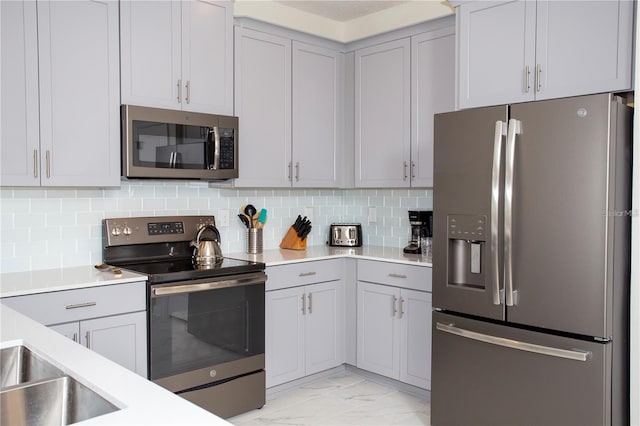 kitchen featuring stainless steel appliances, light tile flooring, and backsplash