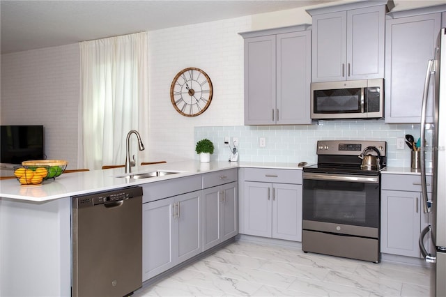 kitchen with gray cabinetry, appliances with stainless steel finishes, sink, tasteful backsplash, and light tile floors