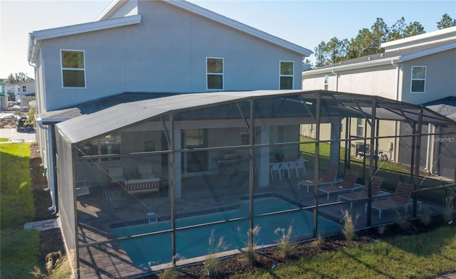 rear view of property featuring glass enclosure and a patio area