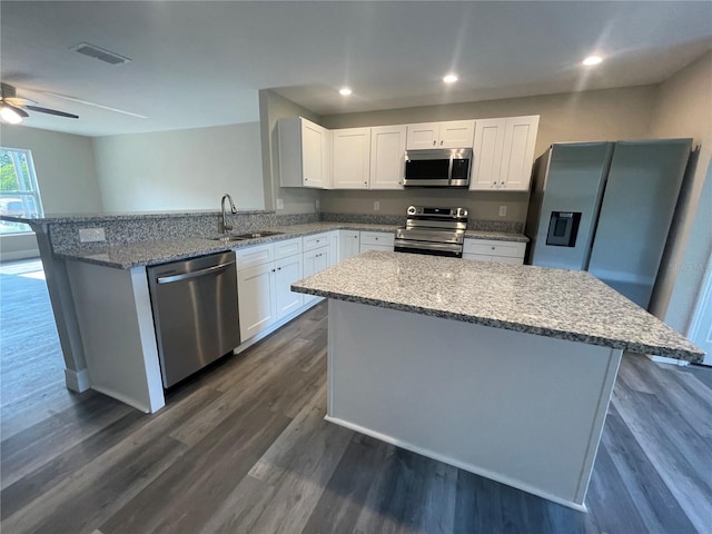 kitchen with appliances with stainless steel finishes, a center island, ceiling fan, sink, and dark wood-type flooring