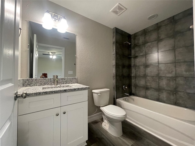 full bathroom with tiled shower / bath, vanity, hardwood / wood-style flooring, toilet, and ceiling fan