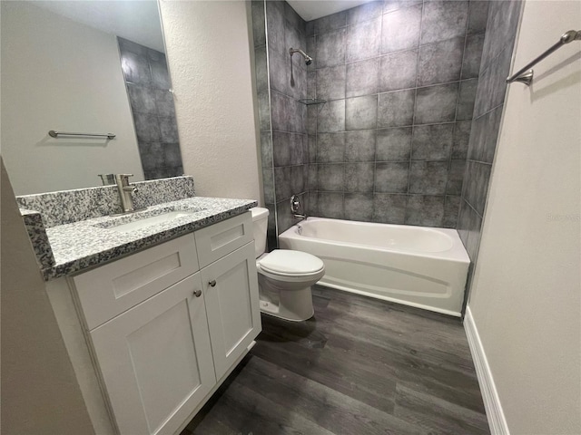 full bathroom featuring wood-type flooring, vanity with extensive cabinet space, toilet, and tiled shower / bath