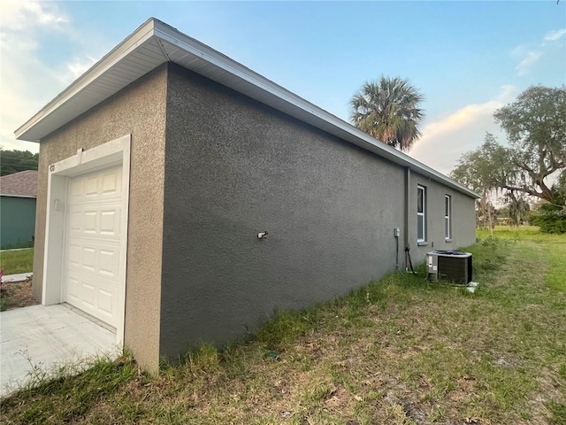 view of property exterior featuring a yard, a garage, and central air condition unit