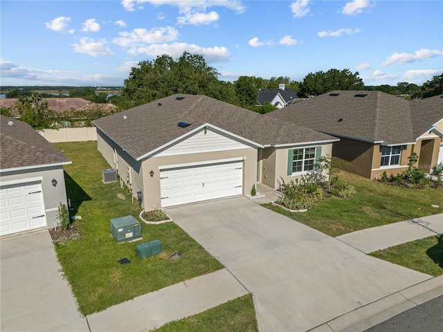 ranch-style home with a garage, a front lawn, and central AC unit