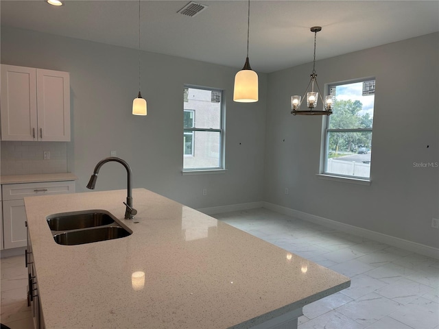 kitchen with sink, tasteful backsplash, light tile floors, and pendant lighting