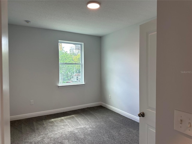 unfurnished room with dark colored carpet and a textured ceiling