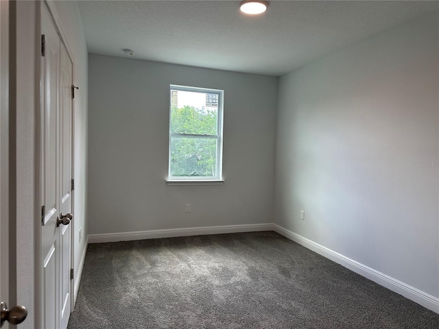 spare room with dark carpet