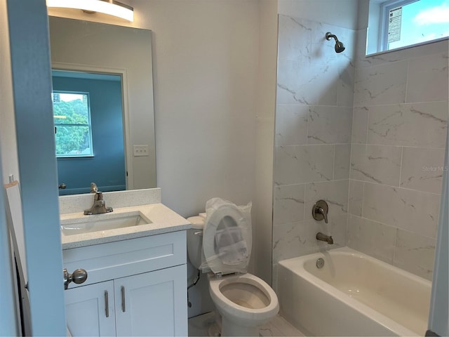 full bathroom featuring vanity with extensive cabinet space, tiled shower / bath combo, and toilet