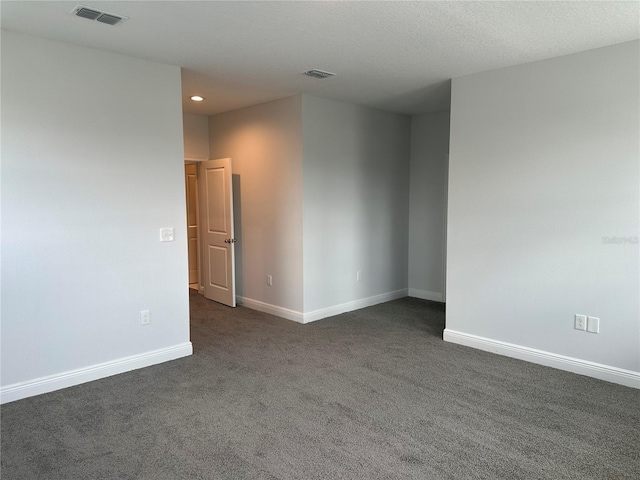 spare room featuring a textured ceiling and dark colored carpet