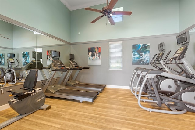 workout area featuring wood-type flooring, ornamental molding, ceiling fan, and a high ceiling