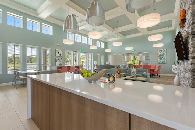 kitchen with a high ceiling, light tile flooring, a wealth of natural light, and coffered ceiling