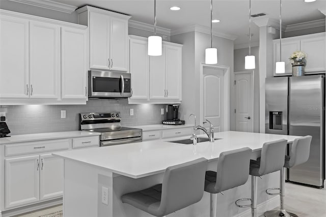 kitchen featuring decorative light fixtures, stainless steel appliances, tasteful backsplash, a kitchen island with sink, and sink