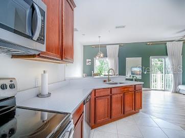 kitchen featuring light tile floors, sink, hanging light fixtures, electric range, and kitchen peninsula