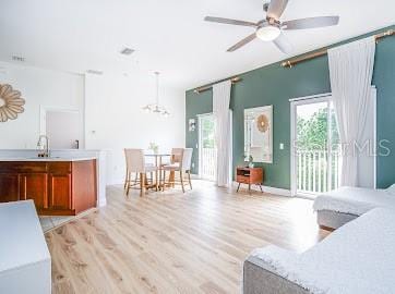 living room featuring sink, light hardwood / wood-style flooring, and ceiling fan