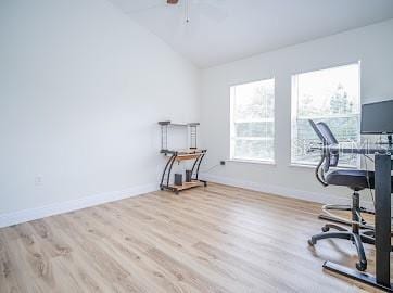 office featuring light hardwood / wood-style floors, ceiling fan, and vaulted ceiling