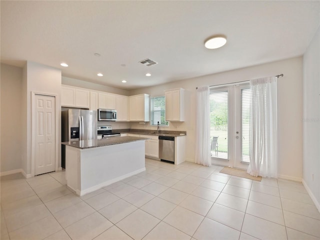 kitchen featuring white cabinetry, a kitchen island, light tile floors, and stainless steel appliances