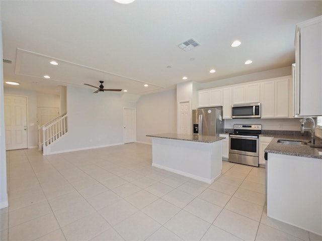 kitchen featuring a center island, stainless steel appliances, sink, ceiling fan, and light tile floors