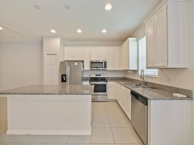 kitchen with appliances with stainless steel finishes, sink, light tile floors, and a kitchen island