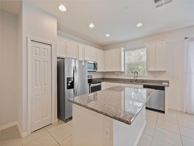 kitchen featuring stainless steel appliances, a kitchen island, white cabinetry, and light tile floors