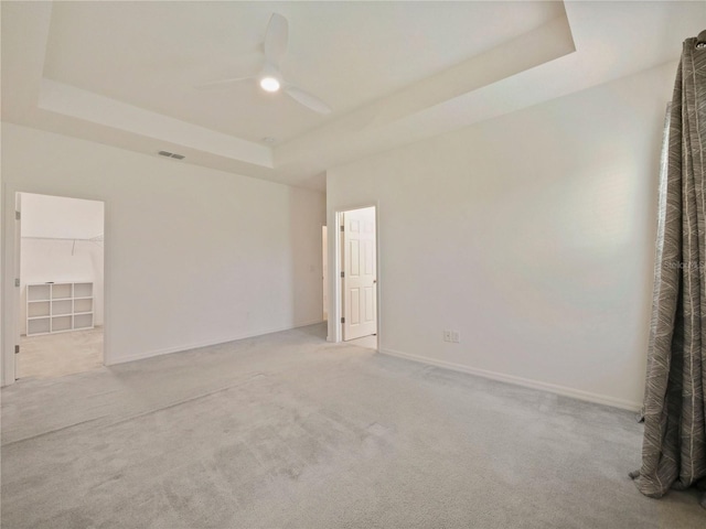 carpeted empty room featuring ceiling fan and a raised ceiling