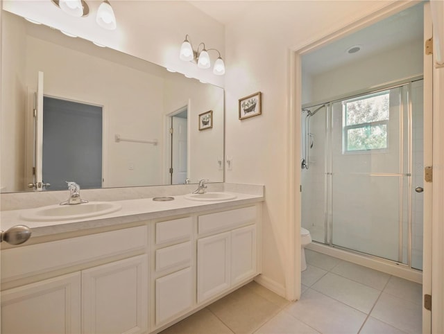 bathroom with tile flooring, a shower with shower door, vanity with extensive cabinet space, toilet, and dual sinks