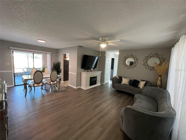 living room featuring ceiling fan, dark hardwood / wood-style floors, and a textured ceiling