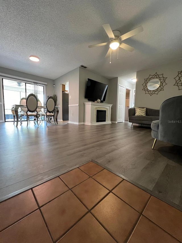 living room with a textured ceiling, ceiling fan, and hardwood / wood-style flooring