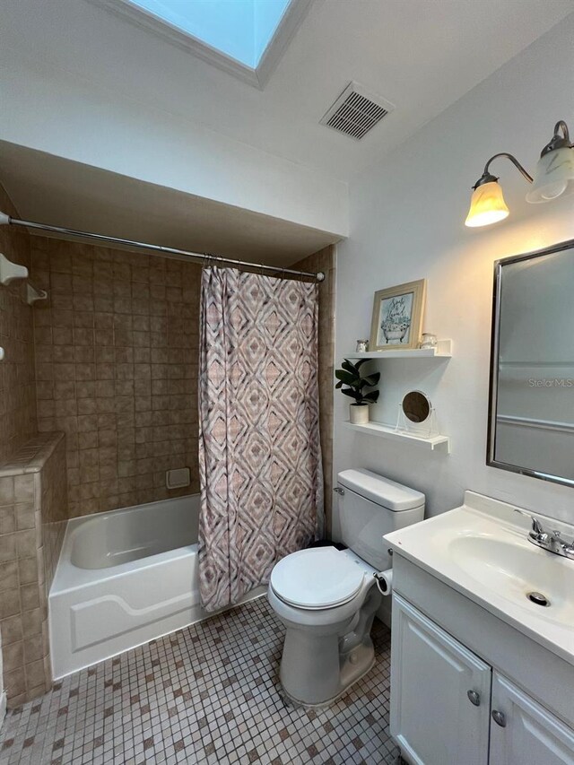 full bathroom featuring a skylight, vanity, shower / bath combo with shower curtain, tile patterned floors, and toilet