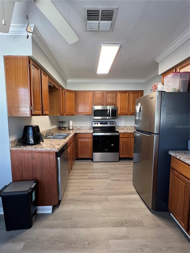 kitchen featuring light wood-type flooring, appliances with stainless steel finishes, sink, and ornamental molding