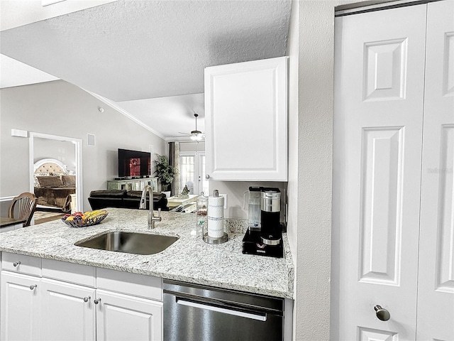 kitchen featuring ceiling fan, sink, white cabinetry, stainless steel dishwasher, and lofted ceiling