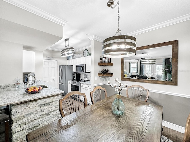 dining space with ornamental molding and sink